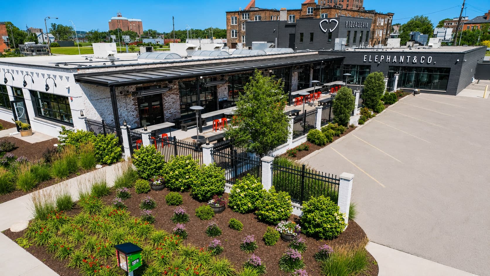 Elephant & Co. pizzeria exterior with white brick, black storefront, covered patio, and landscaped entry