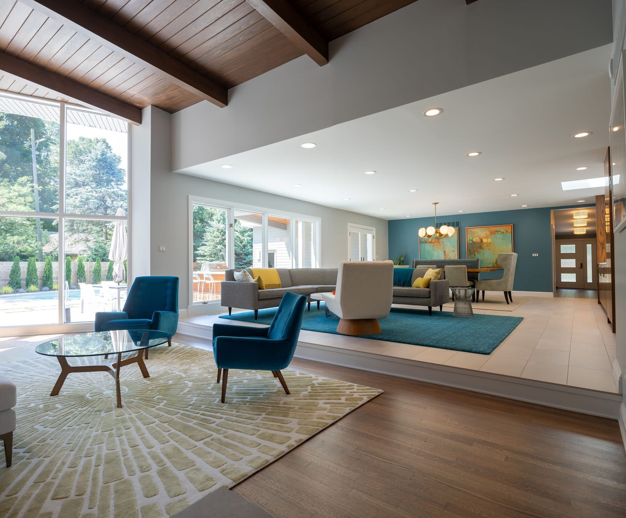 Open living room looking out to pool and backyard through floor-to-ceiling windows
