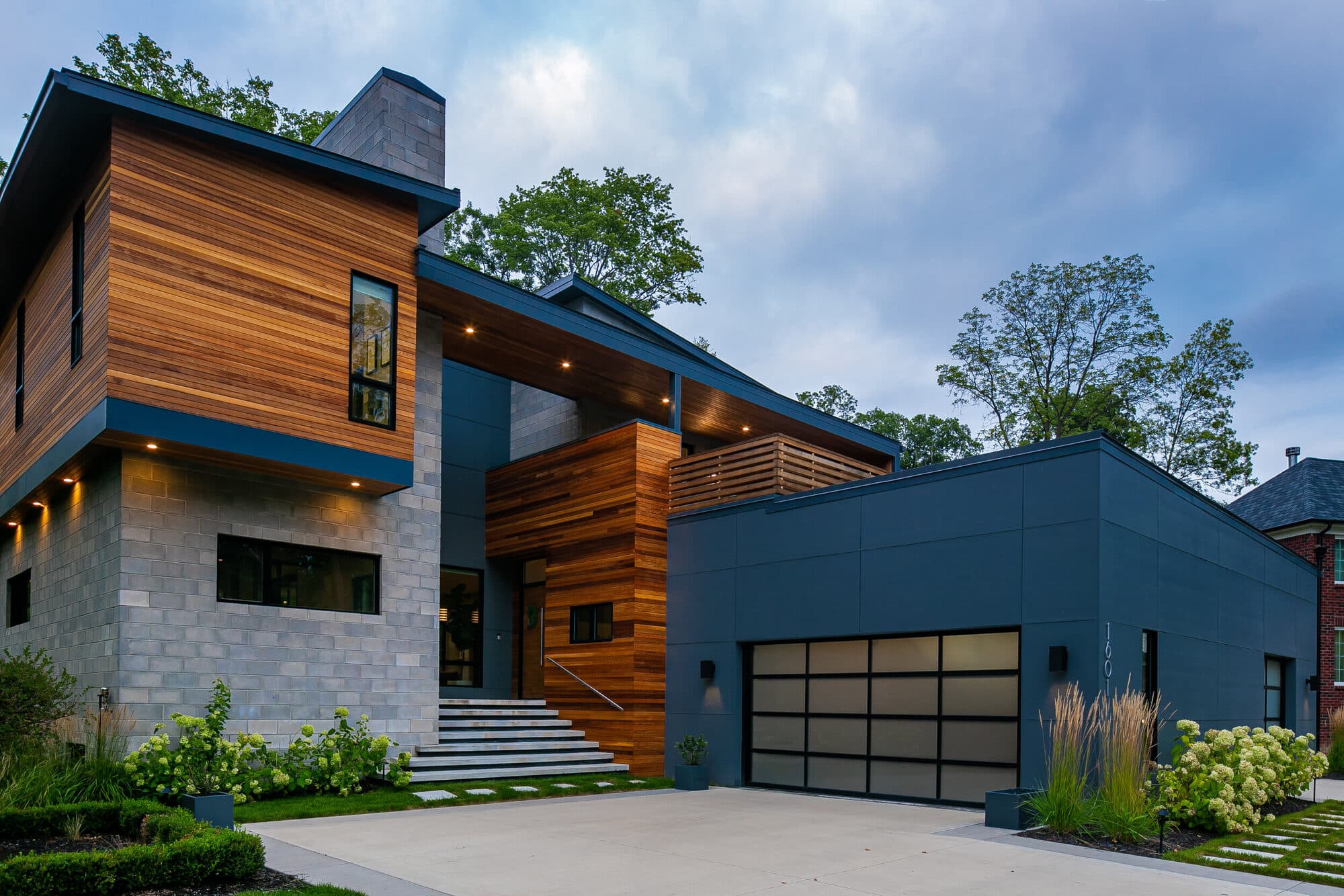 Rochester Private Residence front elevation at dusk with warm interior lighting visible through glass walls