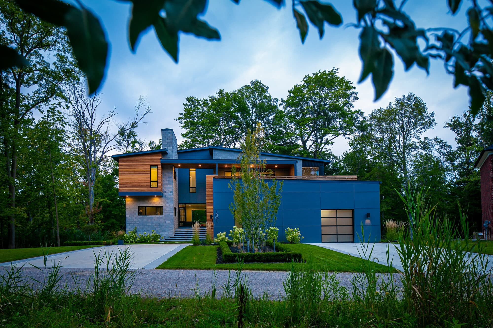 Wide view of modern Rochester residence showing interlocking volumes of stone, wood, and glass